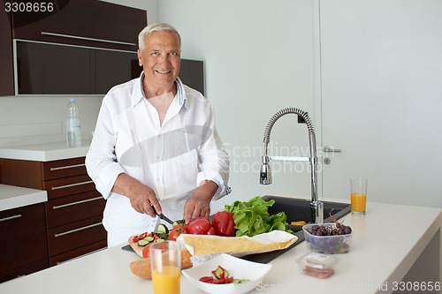 Image of man cooking at home preparing salad in kitchen