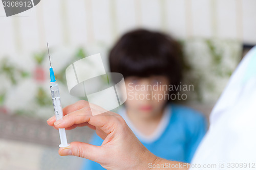 Image of Doctor pediatrician with a syringe and a child in the background