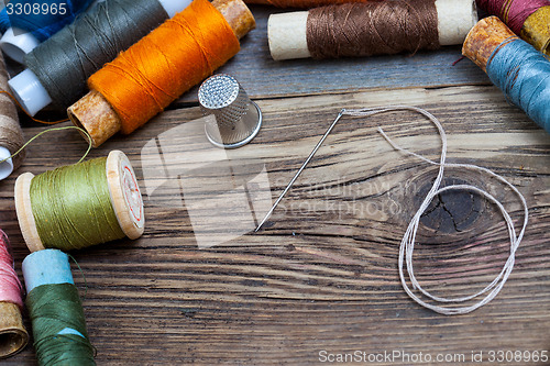 Image of spool of thread, a thimble and a sewing needle