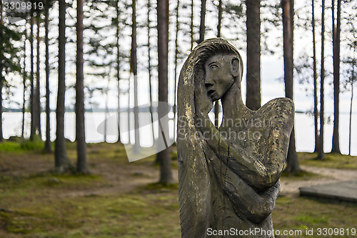 Image of Wooden idol of woman in forest