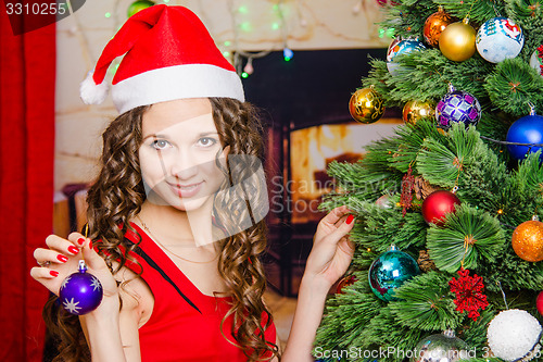 Image of young girl hangs on a Christmas tree ball