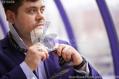 Image of Serious businessman tying his tie