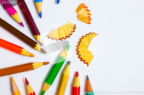 Image of several colored pencils and shavings on white background
