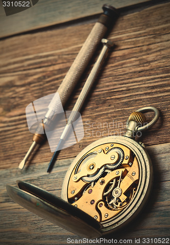 Image of reverse side of the vintage pocket watch and a screwdriver