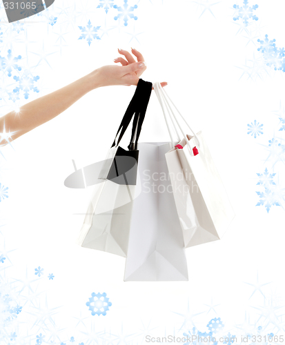 Image of hand with shopping bags and snowflakes