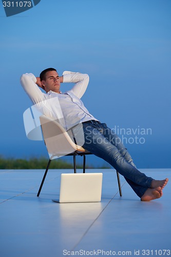 Image of relaxed young man at home on balcony