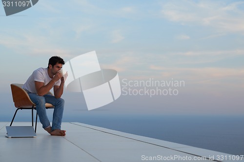 Image of relaxed young man at home on balcony