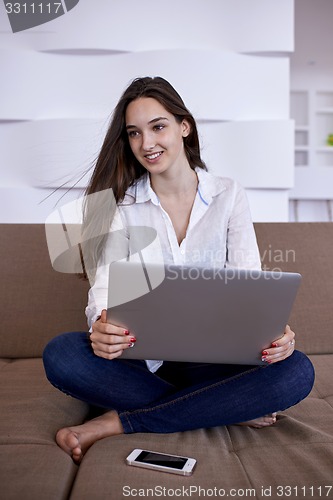 Image of relaxed young woman at home working on laptop computer