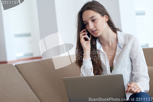 Image of relaxed young woman at home working on laptop computer