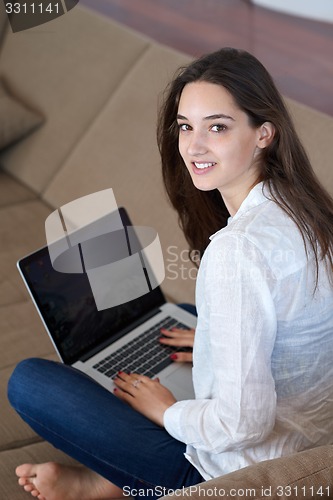 Image of relaxed young woman at home working on laptop computer