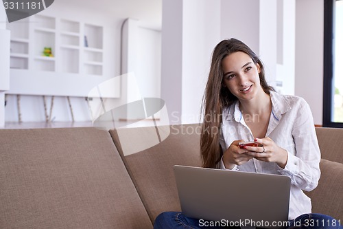 Image of relaxed young woman at home working on laptop computer