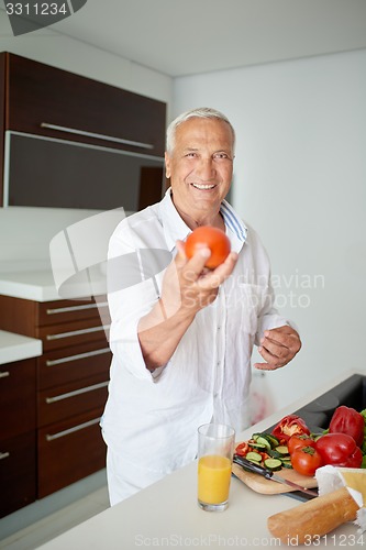 Image of man cooking at home preparing salad in kitchen