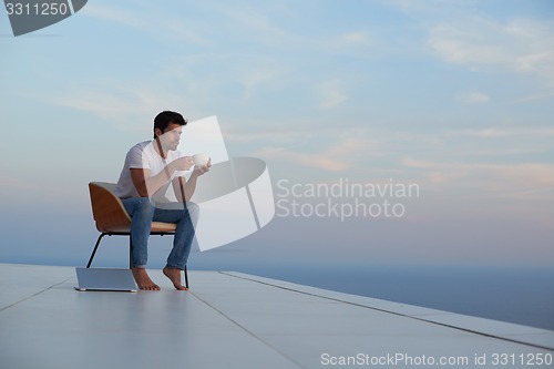 Image of relaxed young man at home on balcony