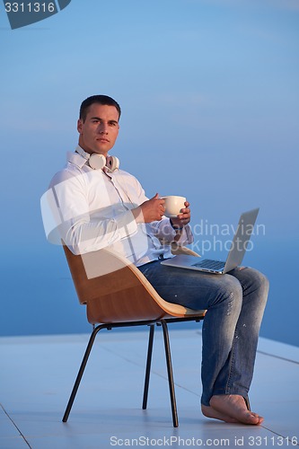 Image of relaxed young man at home on balcony
