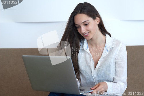 Image of relaxed young woman at home working on laptop computer