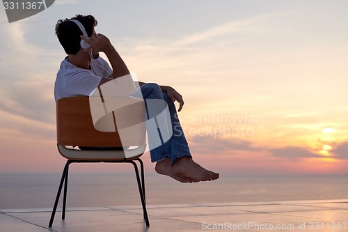 Image of relaxed young man at home on balcony