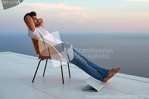 Image of relaxed young man at home on balcony