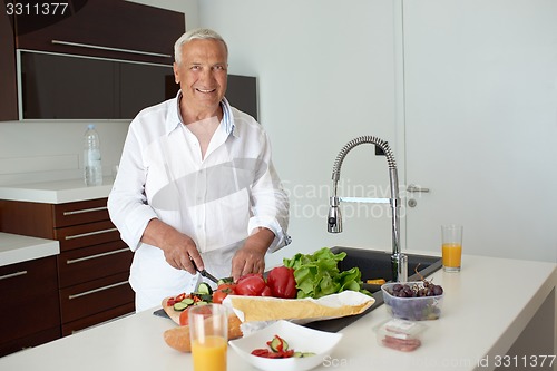 Image of man cooking at home preparing salad in kitchen