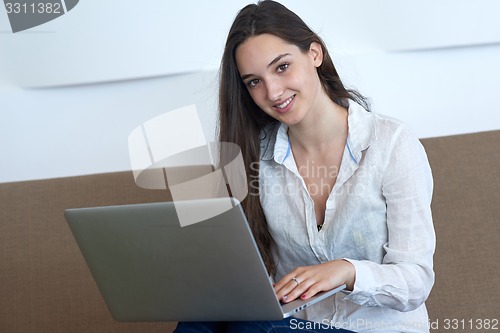 Image of relaxed young woman at home working on laptop computer