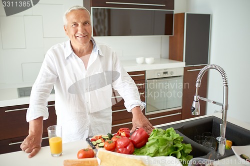 Image of man cooking at home preparing salad in kitchen