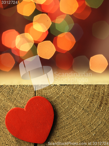 Image of Red heart on the edge of a wooden table.