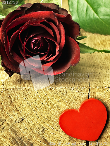 Image of Red rose and red heart on a wooden table.