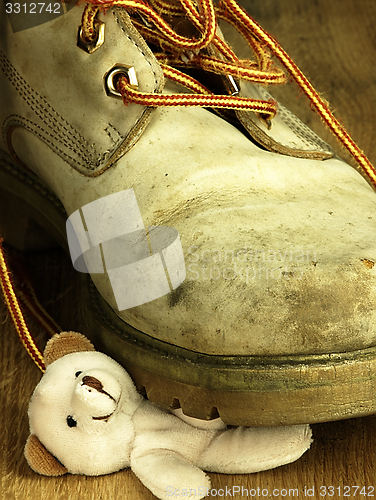 Image of Teddy bear crushed by a heavy, old military boot.