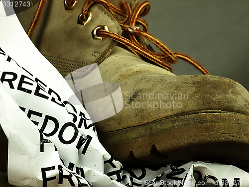 Image of The word freedom crushed by a heavy, old military boot.