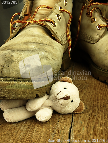 Image of Teddy bear crushed by a heavy, old military boot.