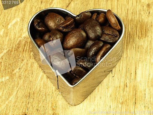 Image of Heart and Coffee beans close-up on wooden, oak table.