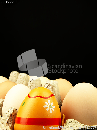 Image of Colorful Easter egg in the company of ordinary eggs.