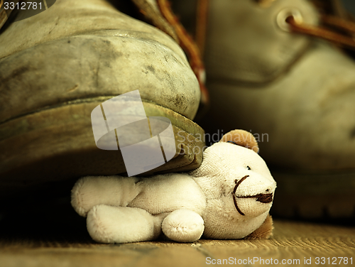 Image of Teddy bear crushed by a heavy, old military boot.