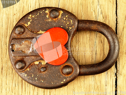 Image of Rusty padlock and heart on a wooden background.