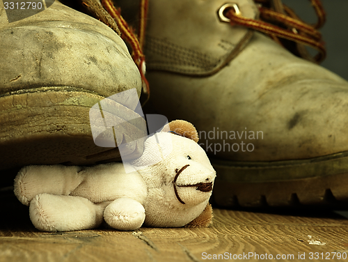 Image of Teddy bear crushed by a heavy, old military boot.