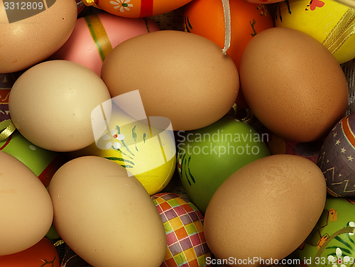 Image of Colorful Easter eggs in the company of ordinary eggs.