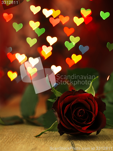 Image of Red rose on a wooden table and hearts.