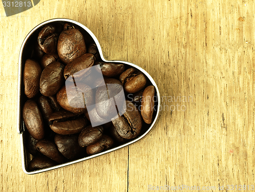 Image of Heart and Coffee beans close-up on wooden, oak table.