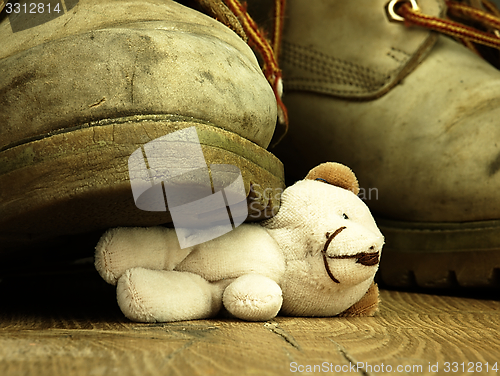 Image of Teddy bear crushed by a heavy, old military boot.