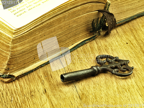 Image of Key and old, open book with a damaged cover.