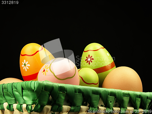 Image of Colorful Easter eggs in the company of ordinary eggs.