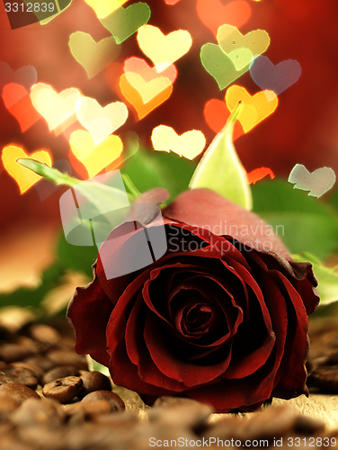 Image of Red rose on a wooden table and hearts.