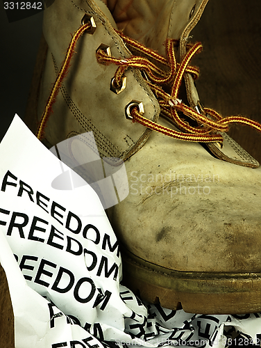 Image of The word freedom crushed by a heavy, old military boot.