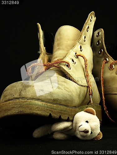 Image of Teddy bear crushed by a heavy, old military boot.