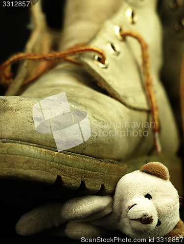 Image of Teddy bear crushed by a heavy, old military boot.