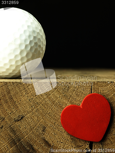 Image of Golf ball and heart on the edge of table.