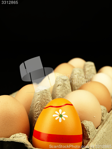 Image of Colorful Easter egg in the company of ordinary eggs.