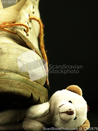 Image of Teddy bear crushed by a heavy, old military boot.