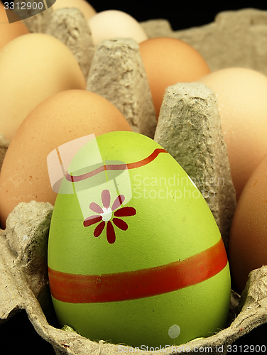 Image of Colorful Easter egg in the company of ordinary eggs.