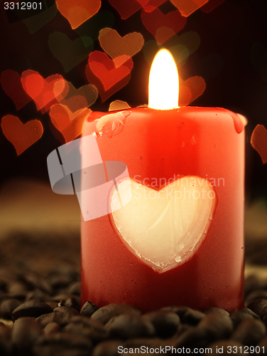 Image of Red candle and coffee on the table. Shiny hearts in background.