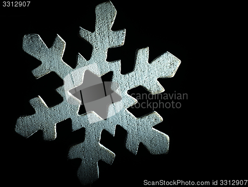 Image of Huge white wooden snowflake and black background.